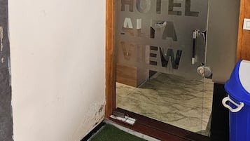 Entrada de un hotel con un letrero de madera que muestra el nombre del hotel y su número de teléfono.