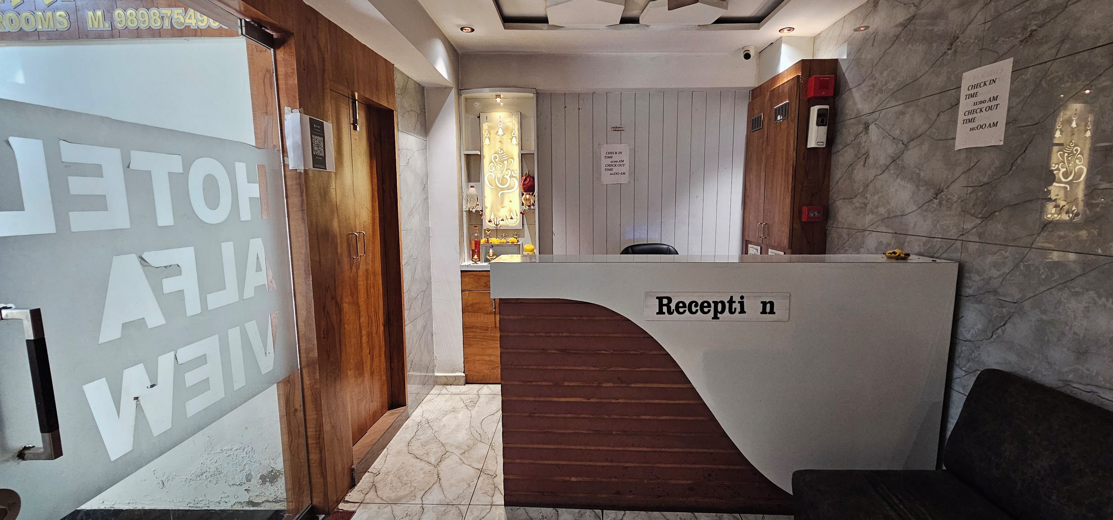 Balcão de recepção com placa indicando 'Recepção' e sinalização com horários de check-in e check-out.
