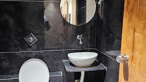 A modern bathroom with a toilet, a sink, and a mirror. - Hotel Alfa View (Ahmedabad)