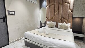 A modern bedroom with a bed, bedside table, and a large mirror. - Hotel Alfa View (Ahmedabad)