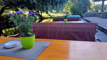 Una mesa de madera con una planta en maceta verde, un posavasos blanco y un mantel individual a rayas.