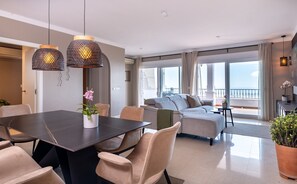 Ein modernes Wohnzimmer mit Essbereich, großen Fenstern und einem Balkon mit Blick.