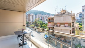 A balcony with a table and chairs, overlooking a cityscape with buildings and a hill. - Maven Studio & Balcony in Jounieh (Jounieh)
