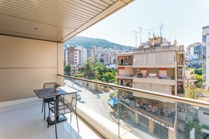 A balcony with a table and chairs, overlooking a cityscape with buildings and a hill. - Maven Studio & Balcony in Jounieh (Jounieh)