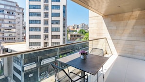A balcony with a table and chairs, overlooking a cityscape with modern buildings. - Maven Studio & Balcony in Jounieh (Jounieh)