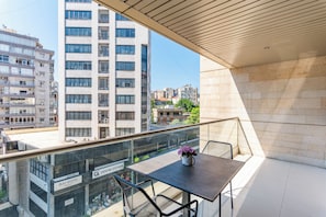 A balcony with a table and chairs, overlooking a cityscape with modern buildings. - Maven Studio & Balcony in Jounieh (Jounieh)