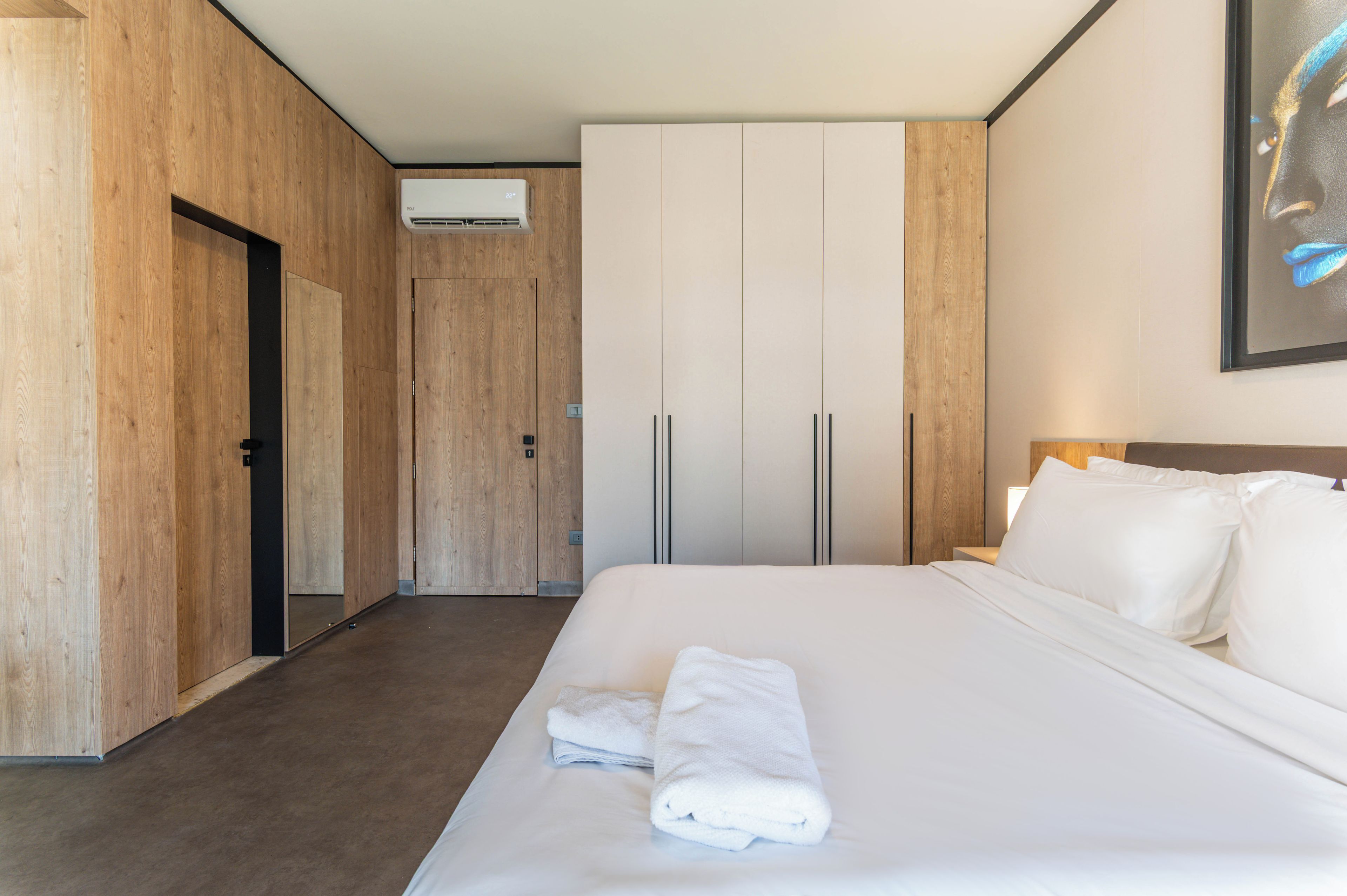 Una habitación de hotel con una cama, un armario, una puerta y un equipo de aire acondicionado.