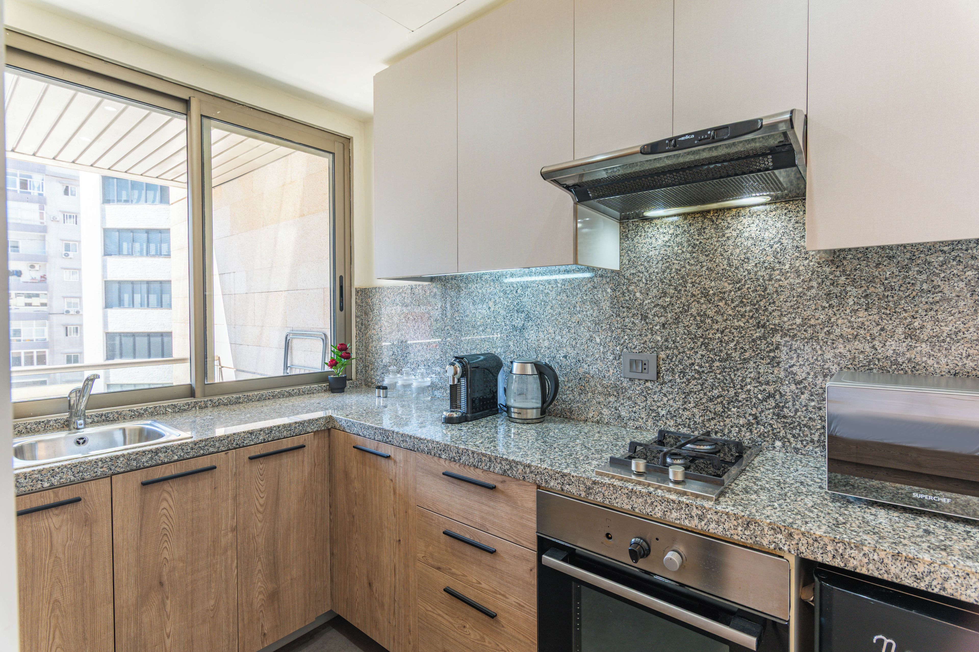 Eine moderne Küche mit Granit-Arbeitsplatten, Edelstahlgeräten und Holzausstattung.