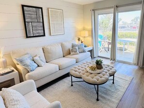 Una sala moderna con sofá, reposapiés y vistas al exterior.