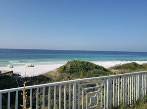 Blick auf einen Strand mit einem weißen Zaun im Vordergrund, feinem Sand und dem Ozean.