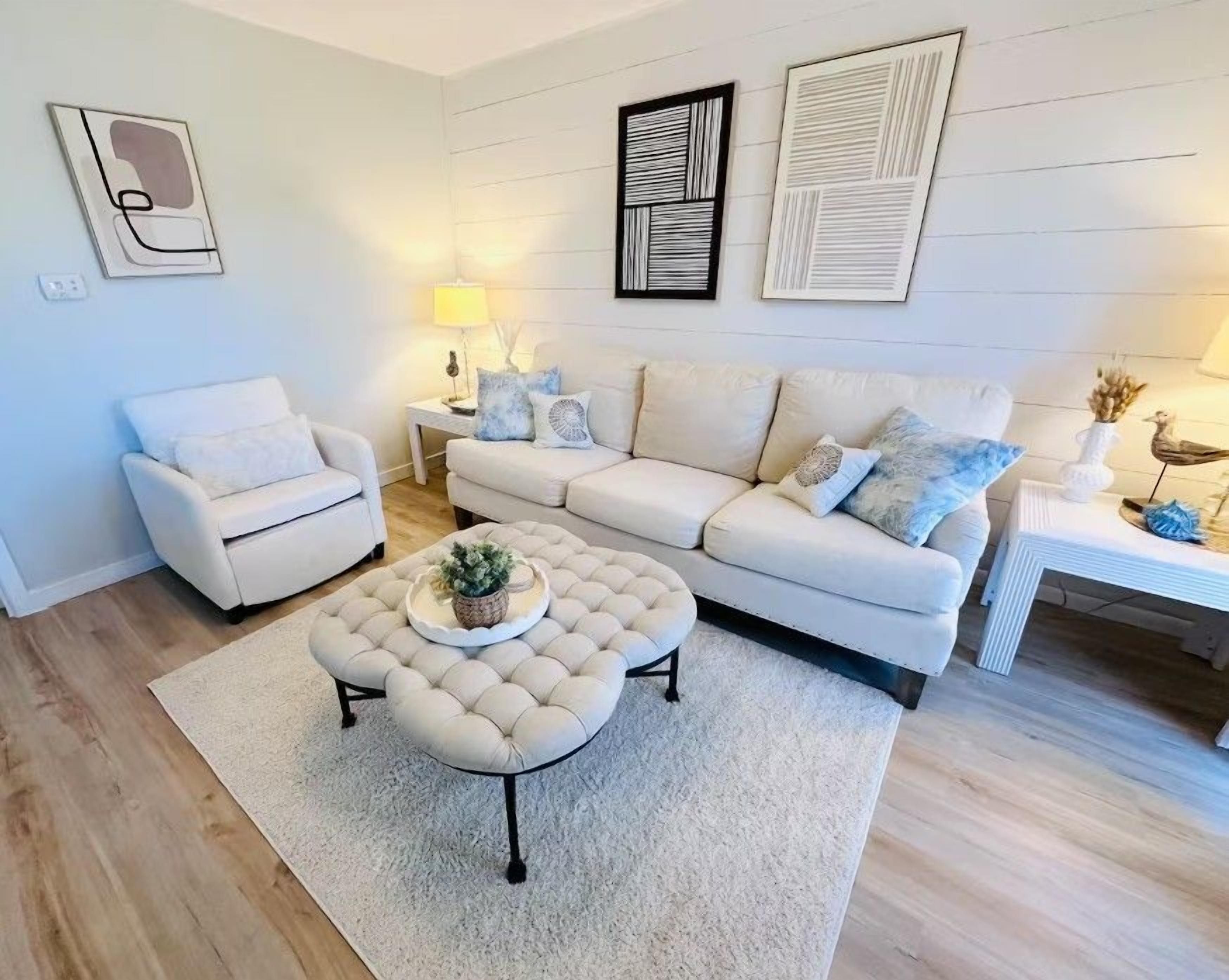 Una sala de estar con un sofá, un sillón, un reposapiés y una mesa de centro.