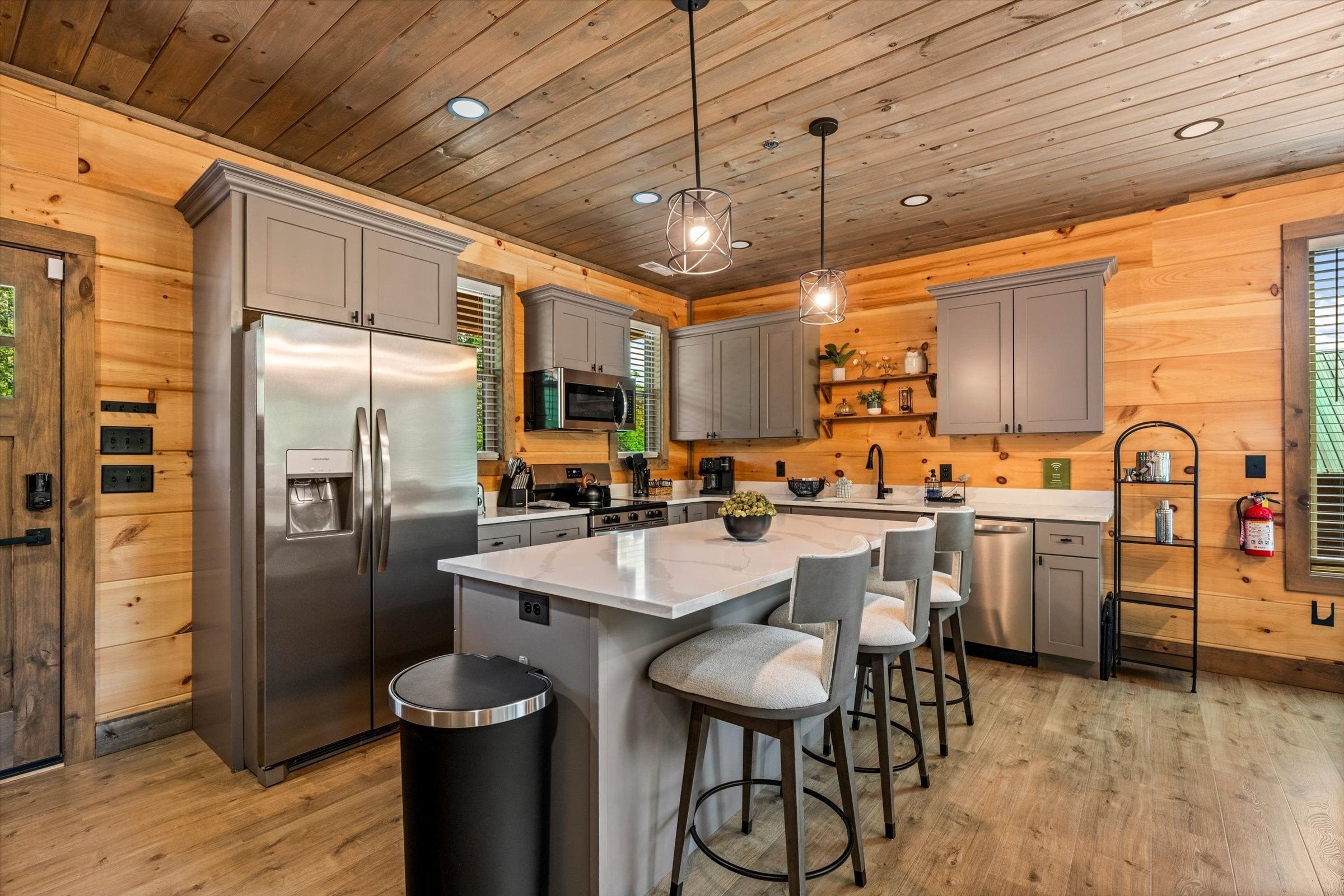 A modern kitchen with a central island, stainless steel appliances, and wooden paneling.