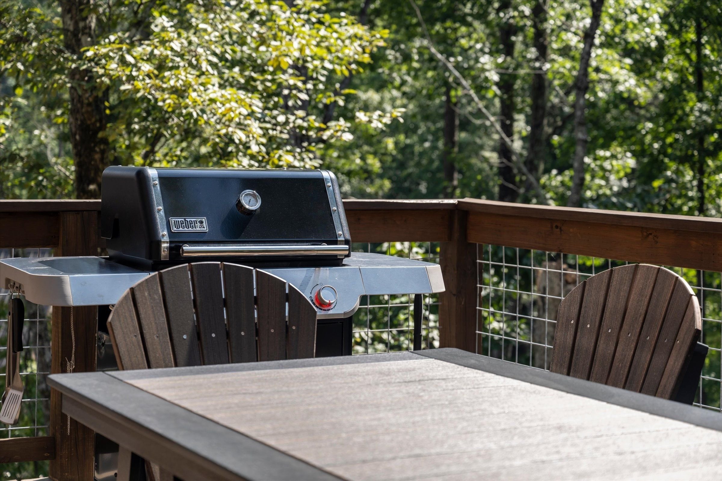 Ein Weber-Grill auf einer Holzterrasse mit Tisch und Stühlen.