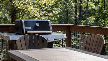 Ein Weber-Grill auf einer Holzterrasse mit Tisch und Stühlen.
