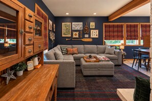 A cozy living room with a sectional sofa, wooden cabinets, and a dining area. - Pinecone Cottage 3 Bedroom Cabin (Leavenworth)