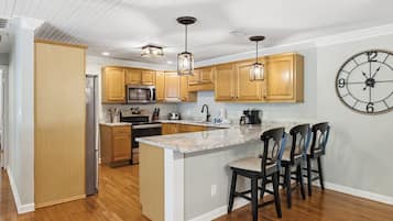 A modern kitchen with wooden cabinets, a built-in microwave, and a large island with bar stools.