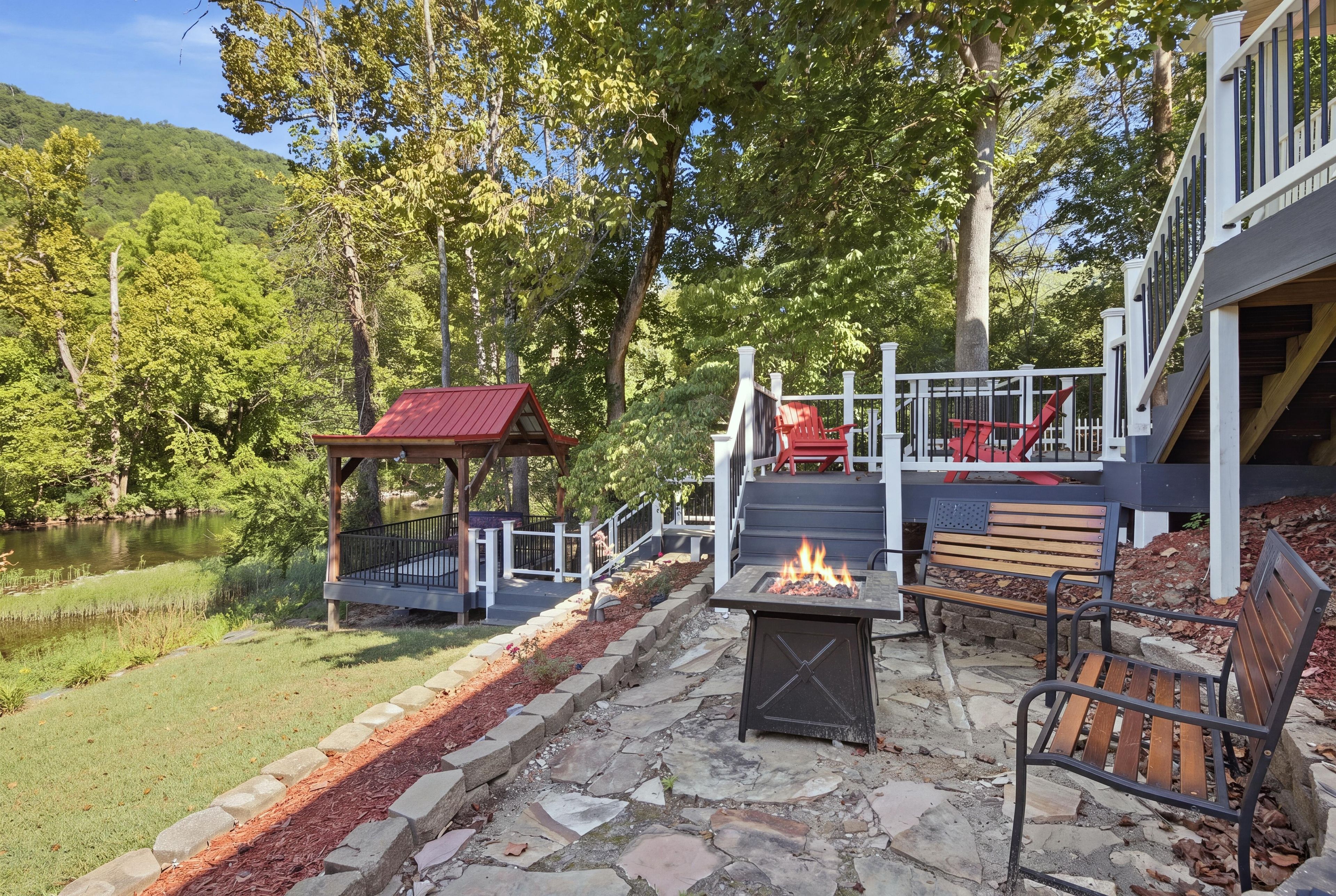 An outdoor patio area with a fire pit, seating, and a covered structure.