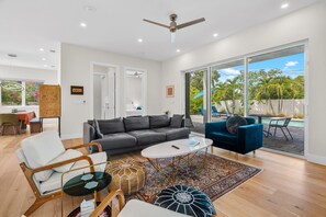 A modern living room with a grey sofa, a blue armchair, and a coffee table. - Paradise Grove 3 Bedroom Home (Sarasota)