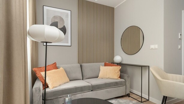 A modern living room with a grey sofa, a round coffee table, a floor lamp, and a side table with a lamp. - Wroclaw | Zwycięska 3 | Comfortable Apartment | Air conditioning (Wrocław)