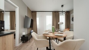 A modern dining area with a round table, four chairs, and a flat-screen TV mounted on the wall. - Wroclaw | Zwycięska 3 | Comfortable Apartment | Air conditioning (Wrocław)