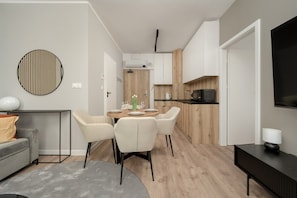 A modern living room with a grey sofa, a round coffee table, and a dining area with a wooden table and chairs.