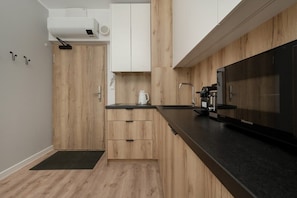 A modern kitchen with wooden cabinetry, a black countertop, and a Hisense microwave.