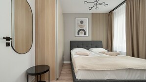 A bedroom with a bed, a round mirror, a small table, and a wall-mounted artwork. - Wroclaw | Zwycięska 3 | Comfortable Apartment | Air conditioning (Wrocław)