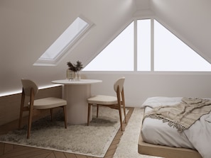 Ein Schlafzimmer mit einem Bett, einem runden Tisch, zwei Stühlen und einem Oberlicht.