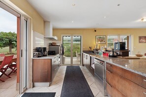 A modern kitchen with a central island, a dishwasher, and a dining area with a red chair.