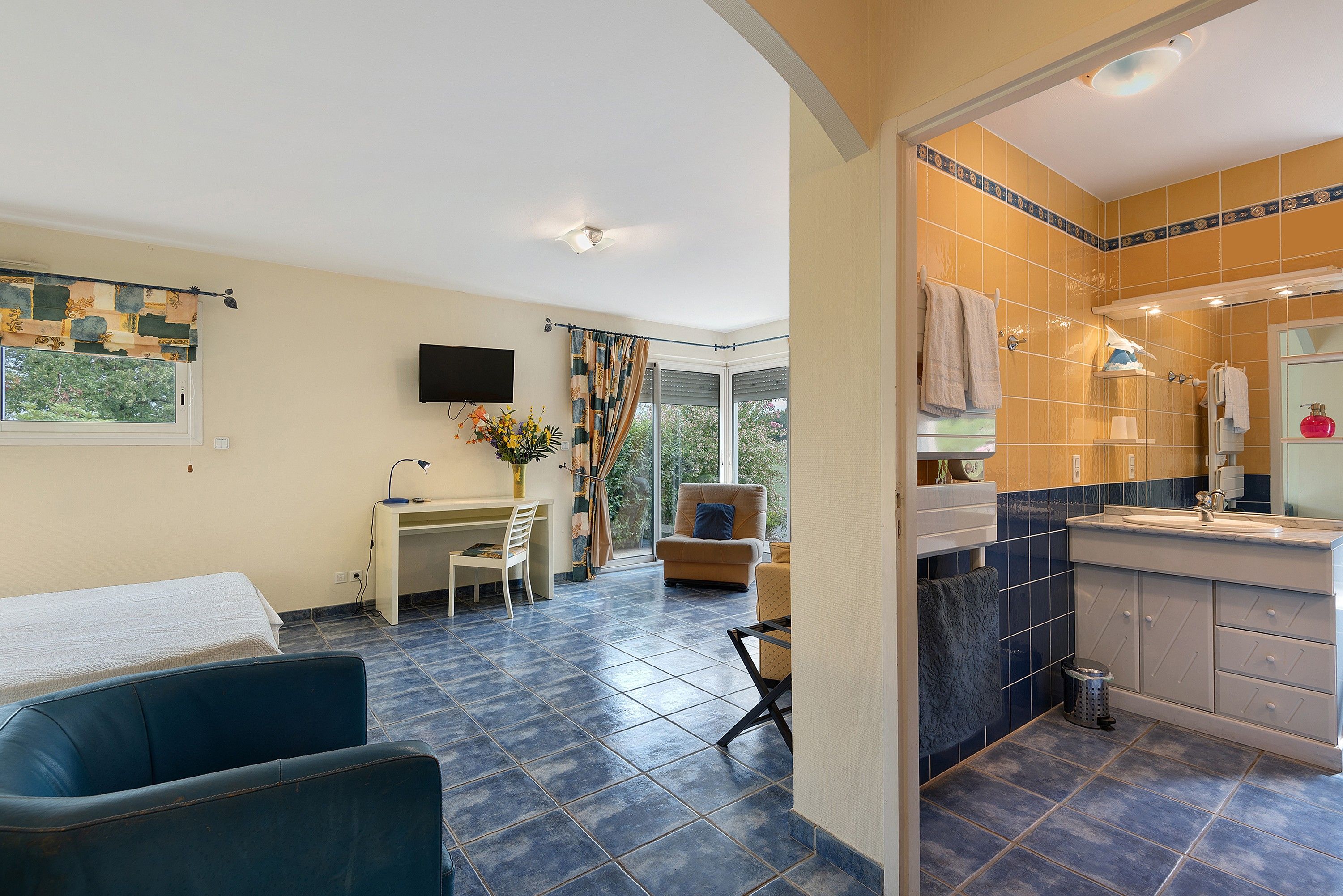 Une chambre d’hôtel équipée d’un bureau, d’une chaise, d’un canapé et d’une salle de bain avec un lavabo et un miroir.