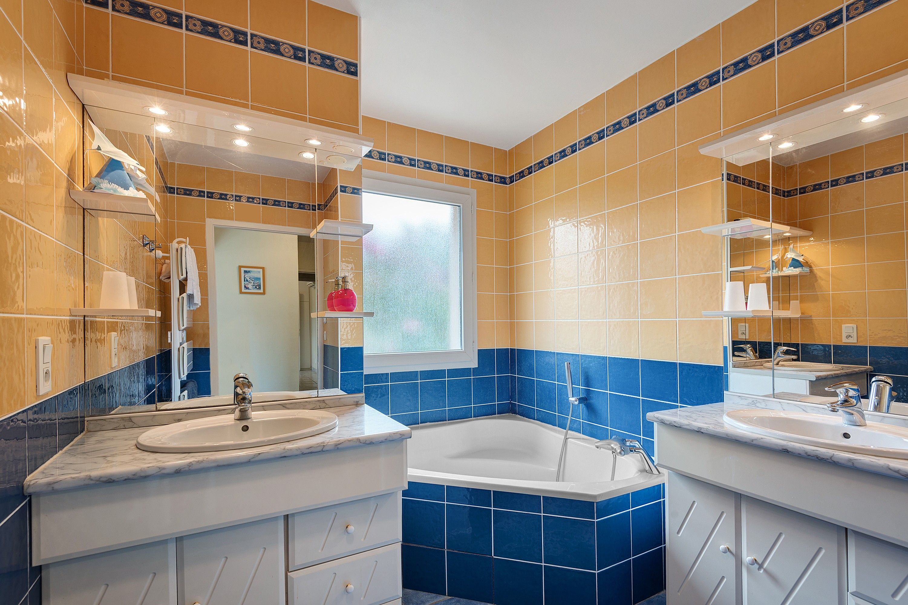 Een badkamer met twee wastafels, een bad en een grote spiegel.