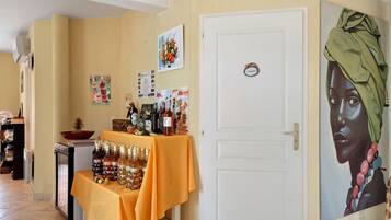 Een kamer met een witte deur, een tafel met flessen en een schilderij aan de muur.