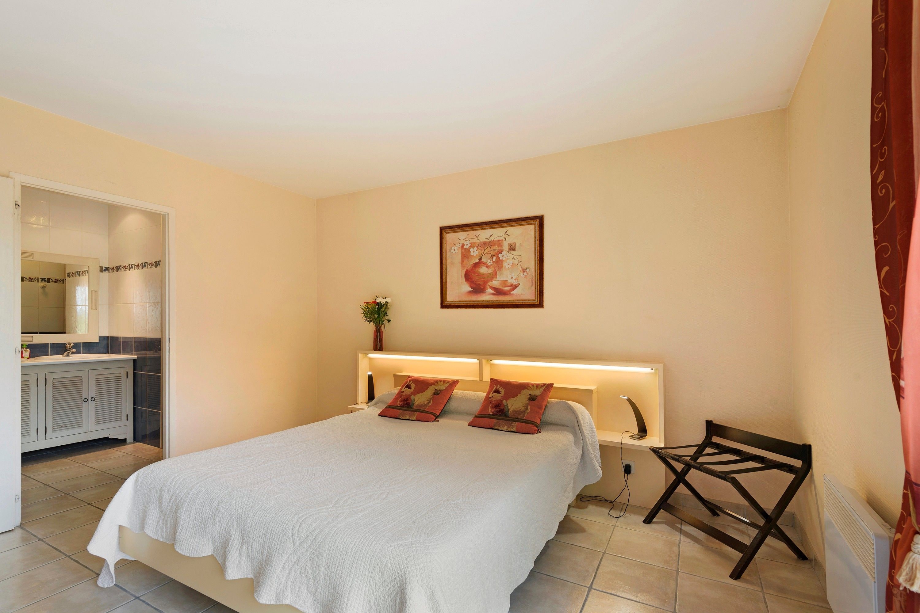Une chambre d’hôtel avec un lit, une table de chevet, une lampe et un tableau au mur.