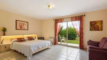 Une chambre à coucher comprenant un lit, un bureau, une chaise, un canapé, une fenêtre avec des rideaux et un tableau accroché au mur.
