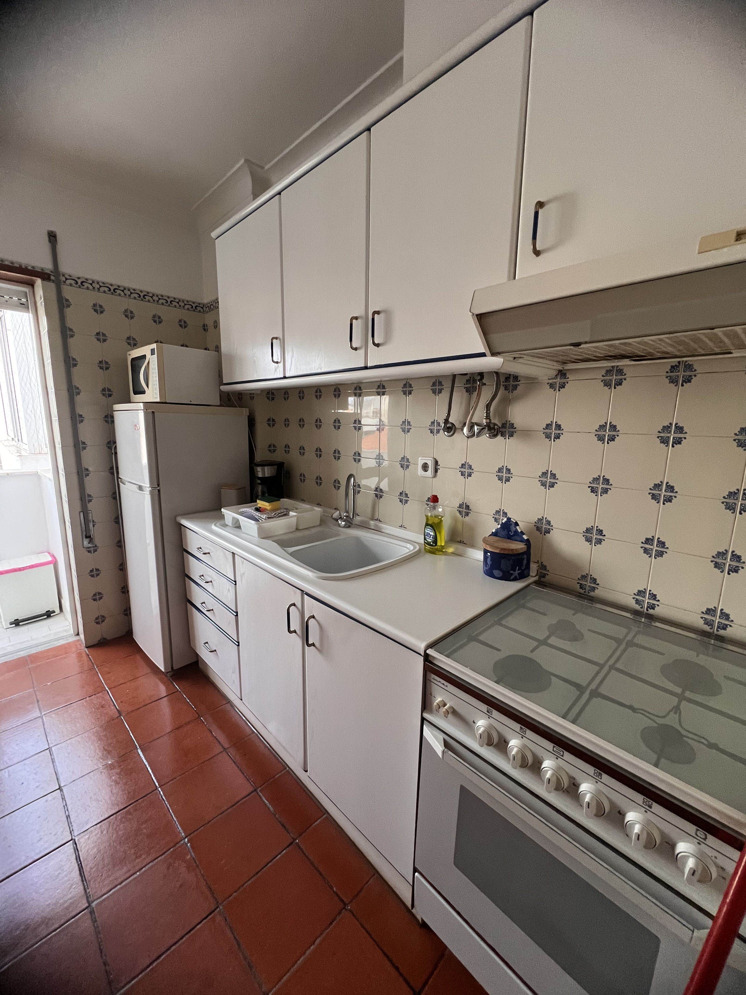 A compact kitchen with white cabinets, a built-in oven, a microwave, and a sink.