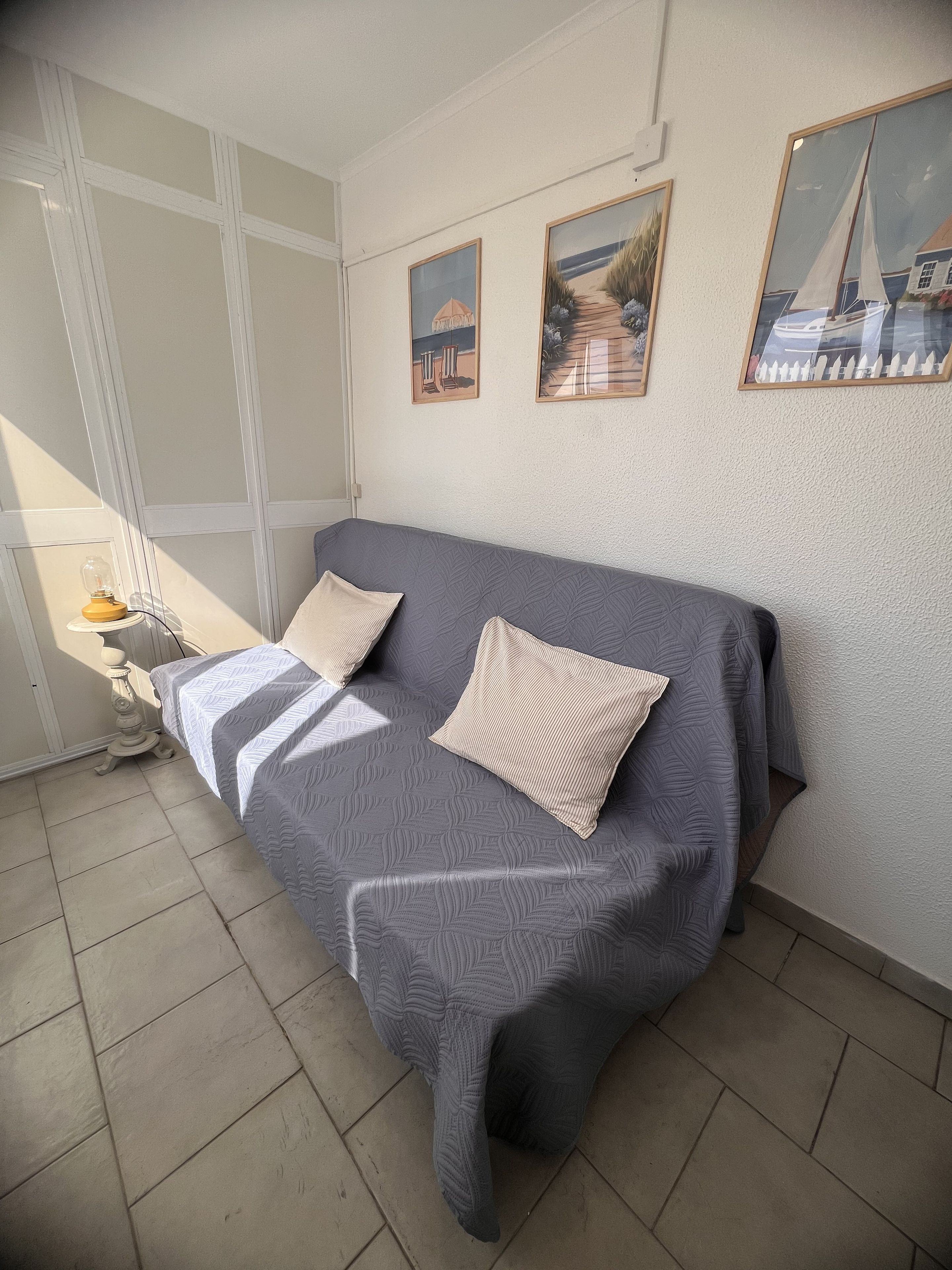 Ein Zimmer mit einem Bett, einem Nachttisch, einer Lampe und gerahmten Bildern an der Wand.