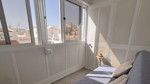 Un dormitorio con cama, mesita de noche y ventana con vista a edificios.