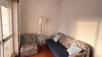 A small room with a sofa, a chair, a lamp, and a window.