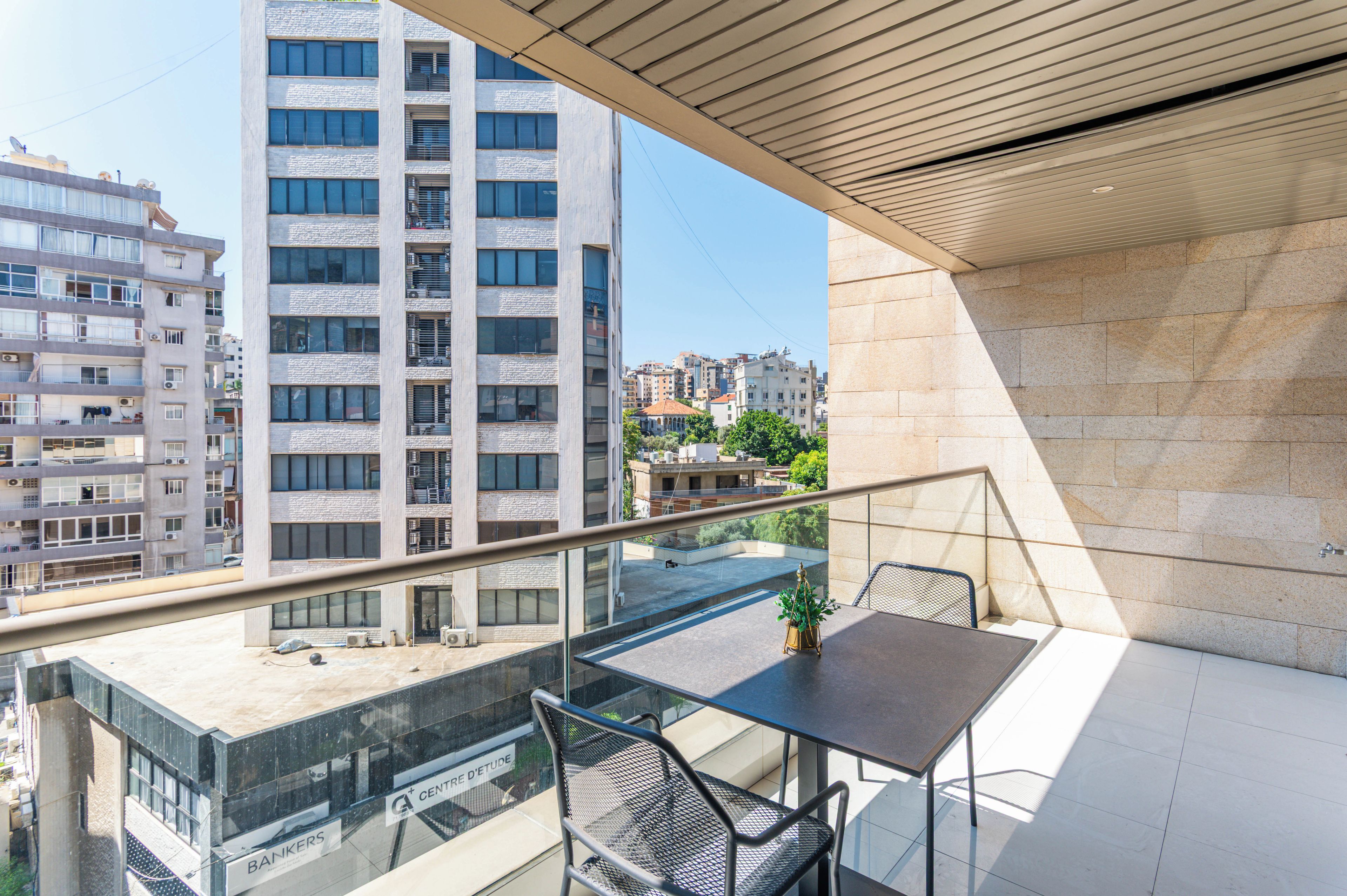 Ein Balkon mit Tisch und Stühlen mit Blick auf eine Skyline moderner Gebäude.