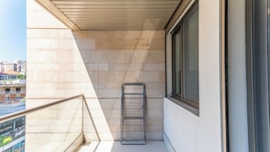 A balcony with a metal rack, a window, and a view of buildings. - Elara Studio & Balcony in Jounieh (Jounieh)