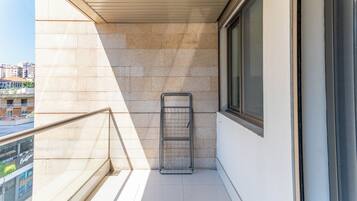 Un balcón con un tendedero de metal, una ventana y vistas a edificios.