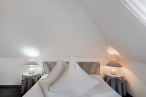 A bedroom with a bed, two bedside tables with lamps, and a checkered headboard. - Apartment 'Warftoase' (Krummhörn Grimersum)