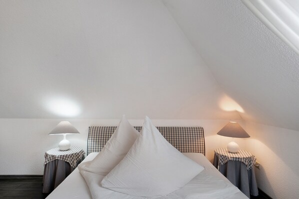 Een slaapkamer met een bed, twee nachtkastjes met lampen en een geruit hoofdeinde.