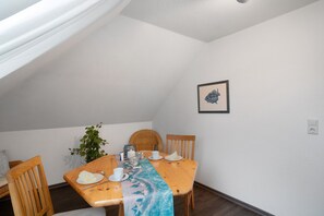 A dining area with a wooden table, chairs, a plant, and a framed picture on the wall. - Apartment 'Warftoase' (Krummhörn Grimersum)