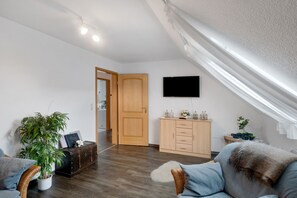 A living room with a wooden door, a flat-screen TV, a cabinet, and a plant. - Apartment 'Warftoase' (Krummhörn Grimersum)