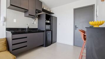 Une cuisine moderne avec des meubles de rangement aux couleurs sombres, un four à micro-ondes encastré et une machine à café.