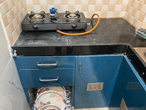 Una cocina con estufa a gas, un armario azul y un escurreplatos.