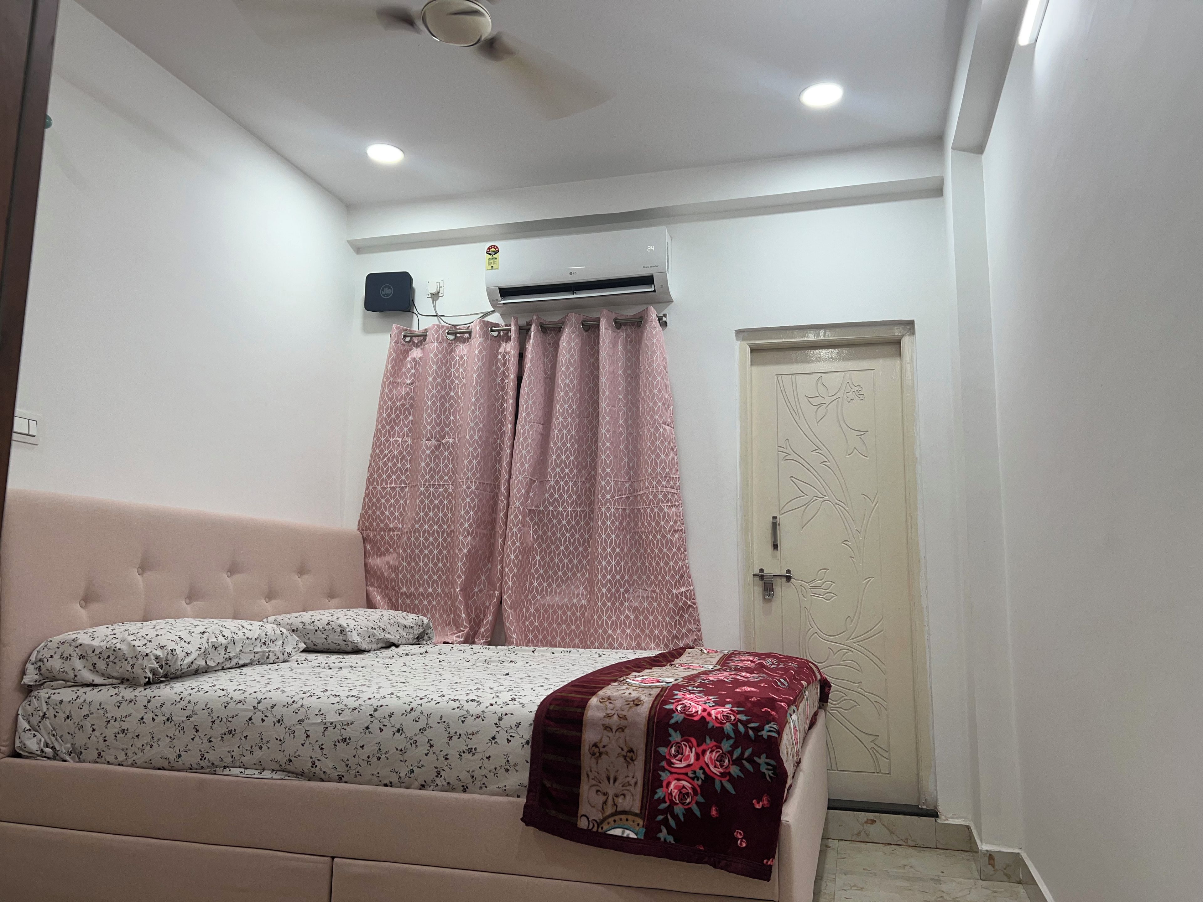 Un dormitorio con cama, armario, puerta y equipo de aire acondicionado.