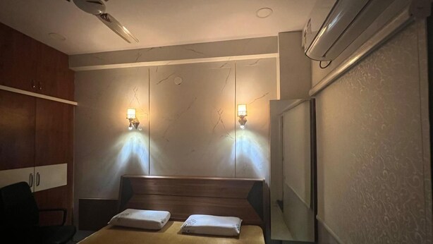 Ein Hotelzimmer mit einem Bett, zwei Nachttischlampen, einem Deckenventilator und einer Klimaanlage.