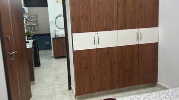 Un dormitorio con un armario grande, una cama con cubrecama floral y un baño visible a través de una puerta abierta.